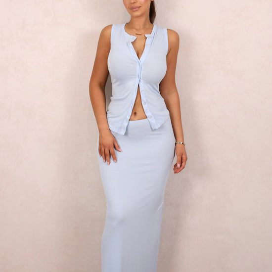 A model wearing a baby blue ribbed knit two-piece set with a button-up tank and matching maxi skirt.