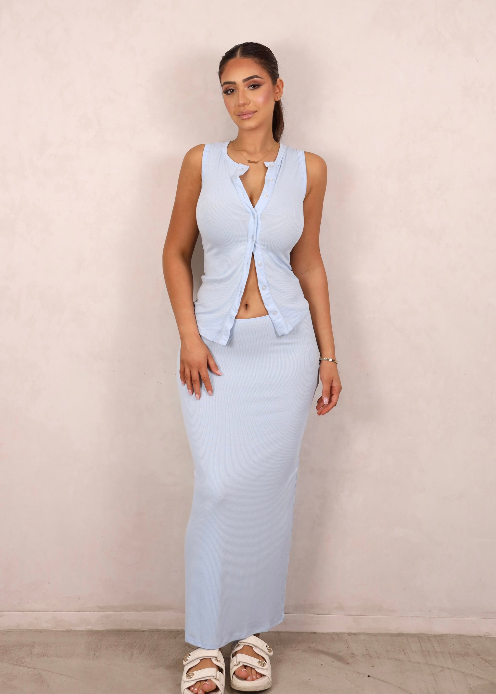 A model wearing a baby blue ribbed knit two-piece set with a button-up tank and matching maxi skirt.