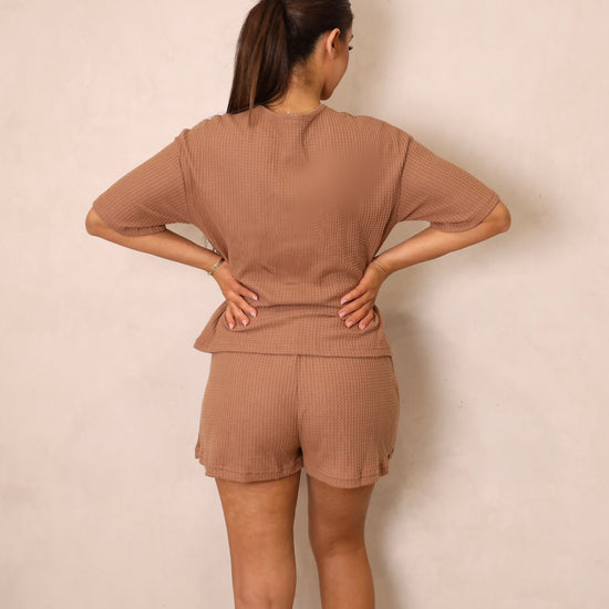 A woman wearing a brown tie-front crop top and matching shorts with a drawstring waist.