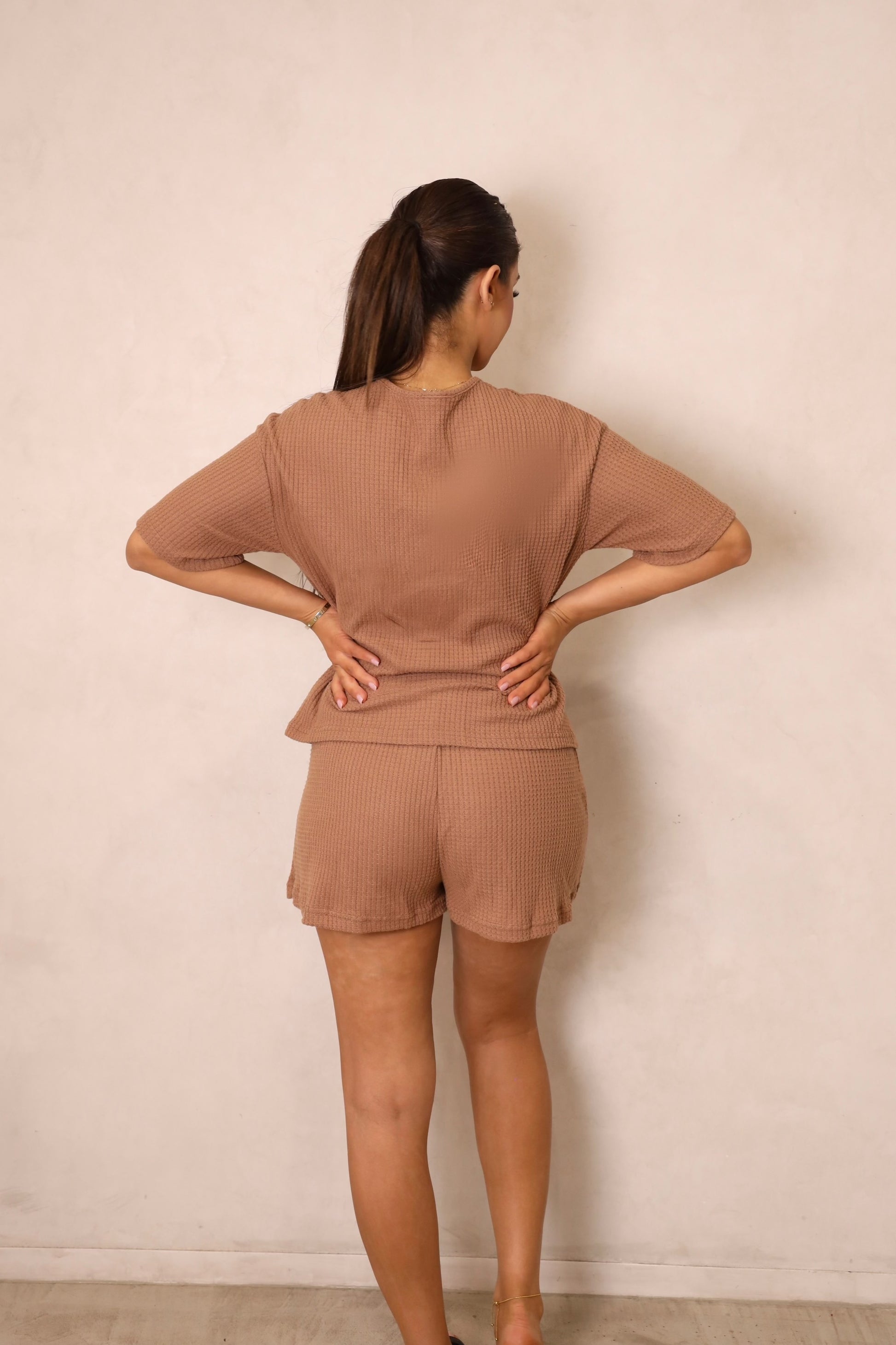 A woman wearing a brown tie-front crop top and matching shorts with a drawstring waist.