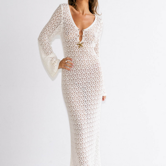 Woman wearing a white lace dress with sheer sleeves against a plain background