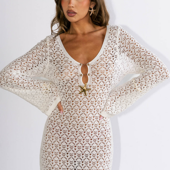 Woman wearing a white lace dress with a starfish brooch on a white background