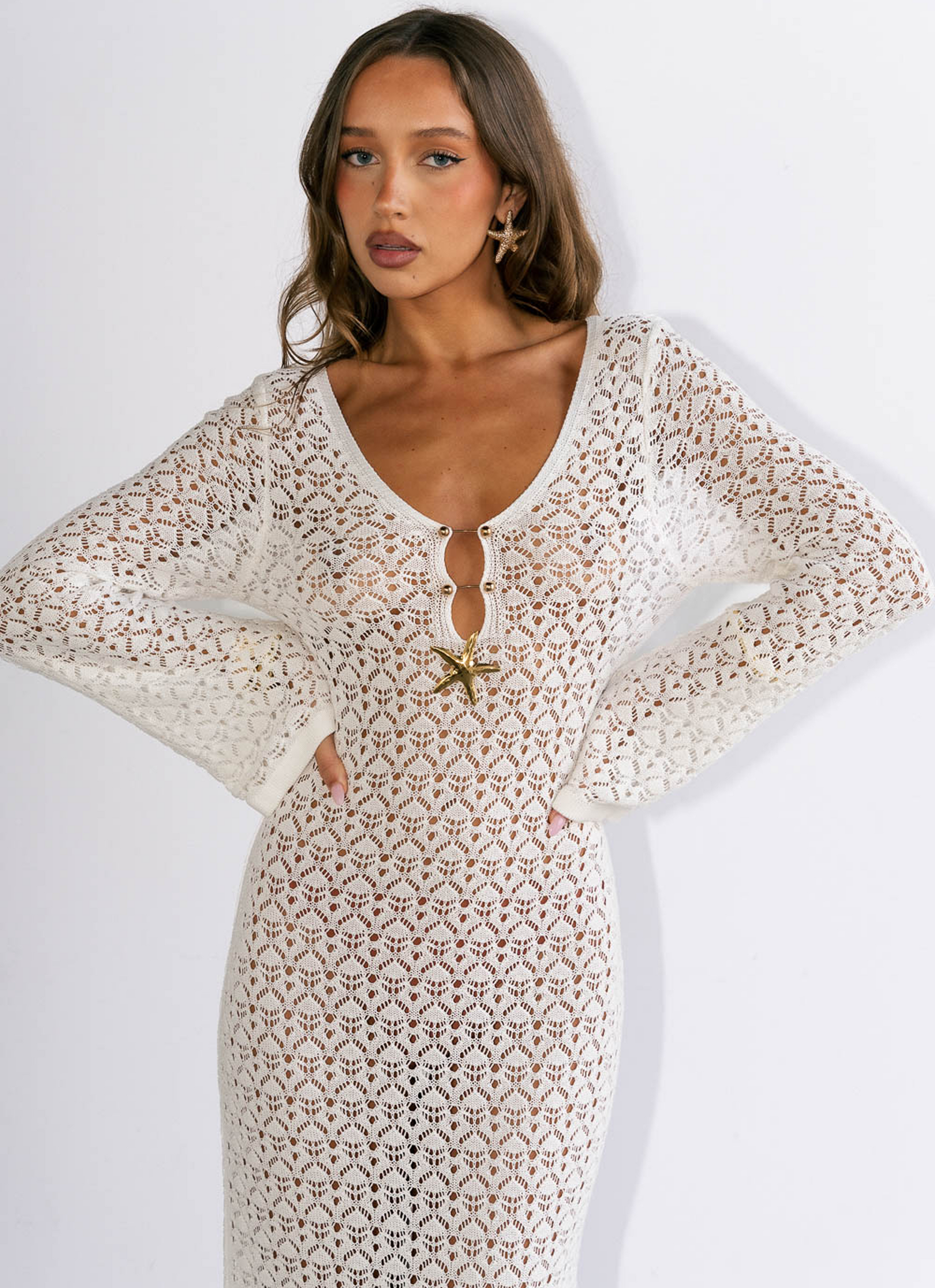 Woman wearing a white lace dress with a starfish brooch on a white background