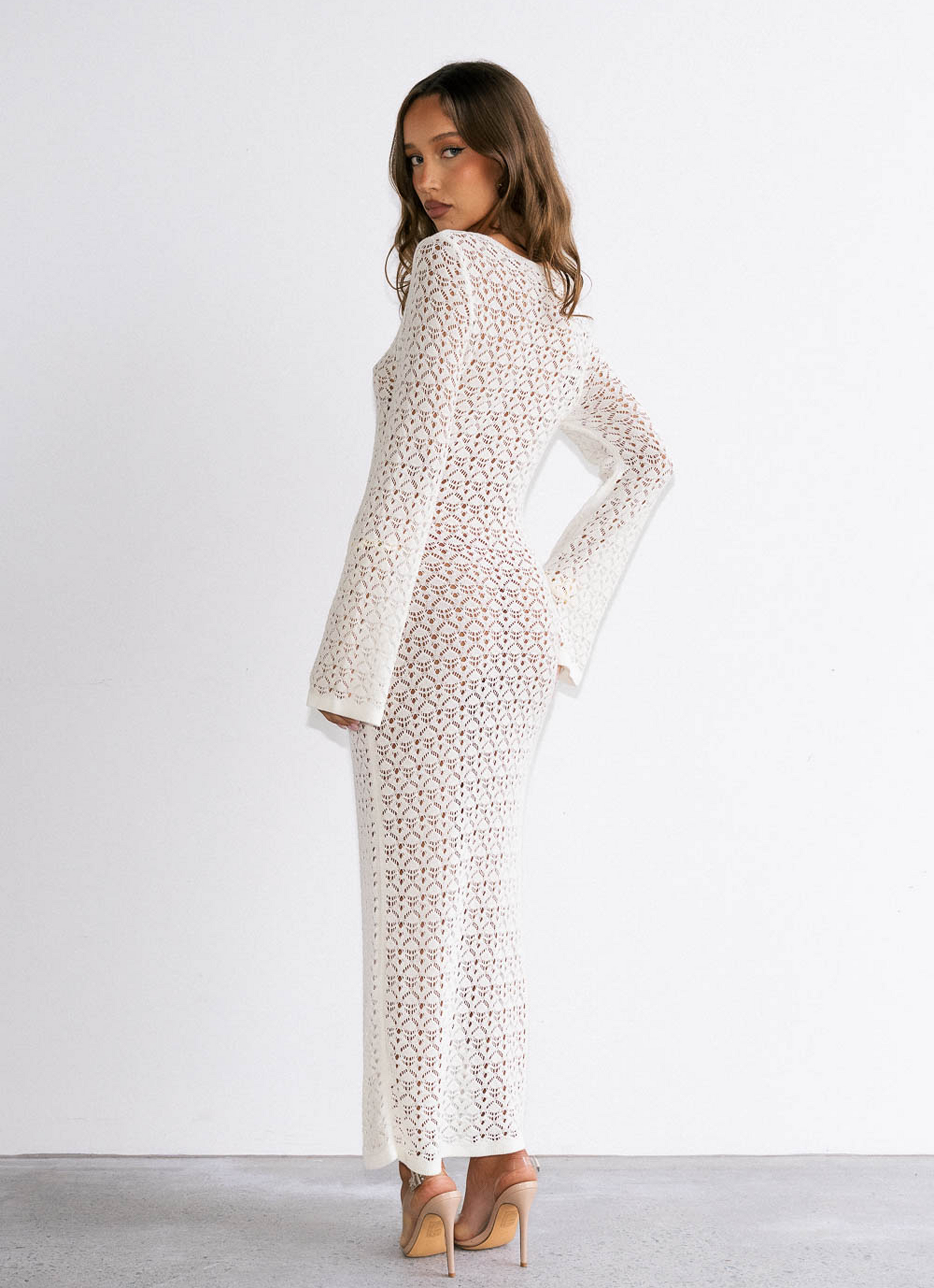 Woman wearing a white dress with a subtle pattern on a plain background