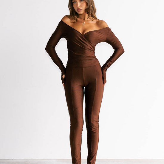 Woman wearing a brown off-shoulder jumpsuit on a white background