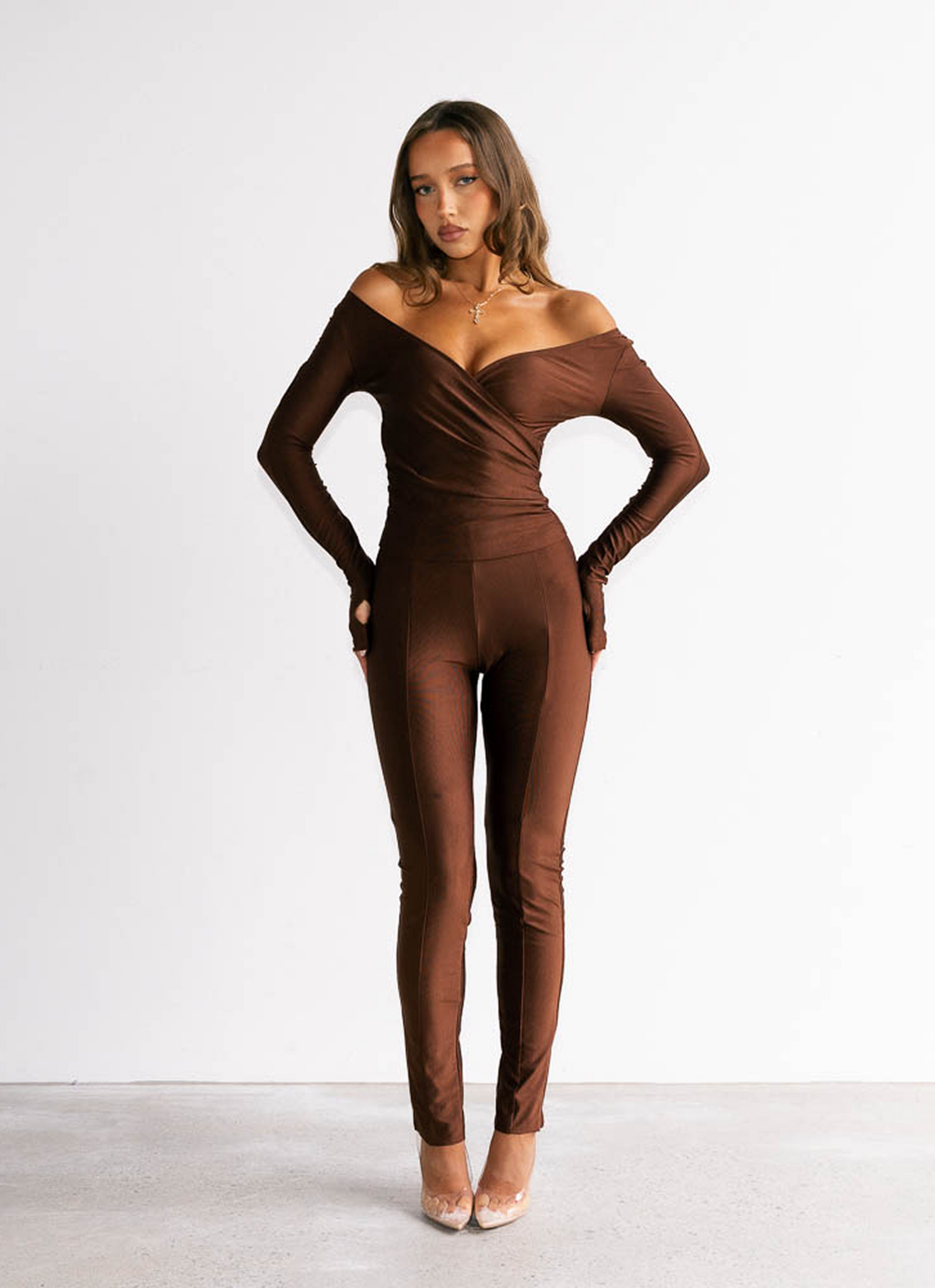Woman wearing a brown off-shoulder jumpsuit on a white background