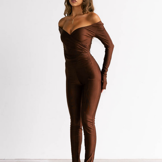 Woman wearing a brown off-shoulder jumpsuit on a white background