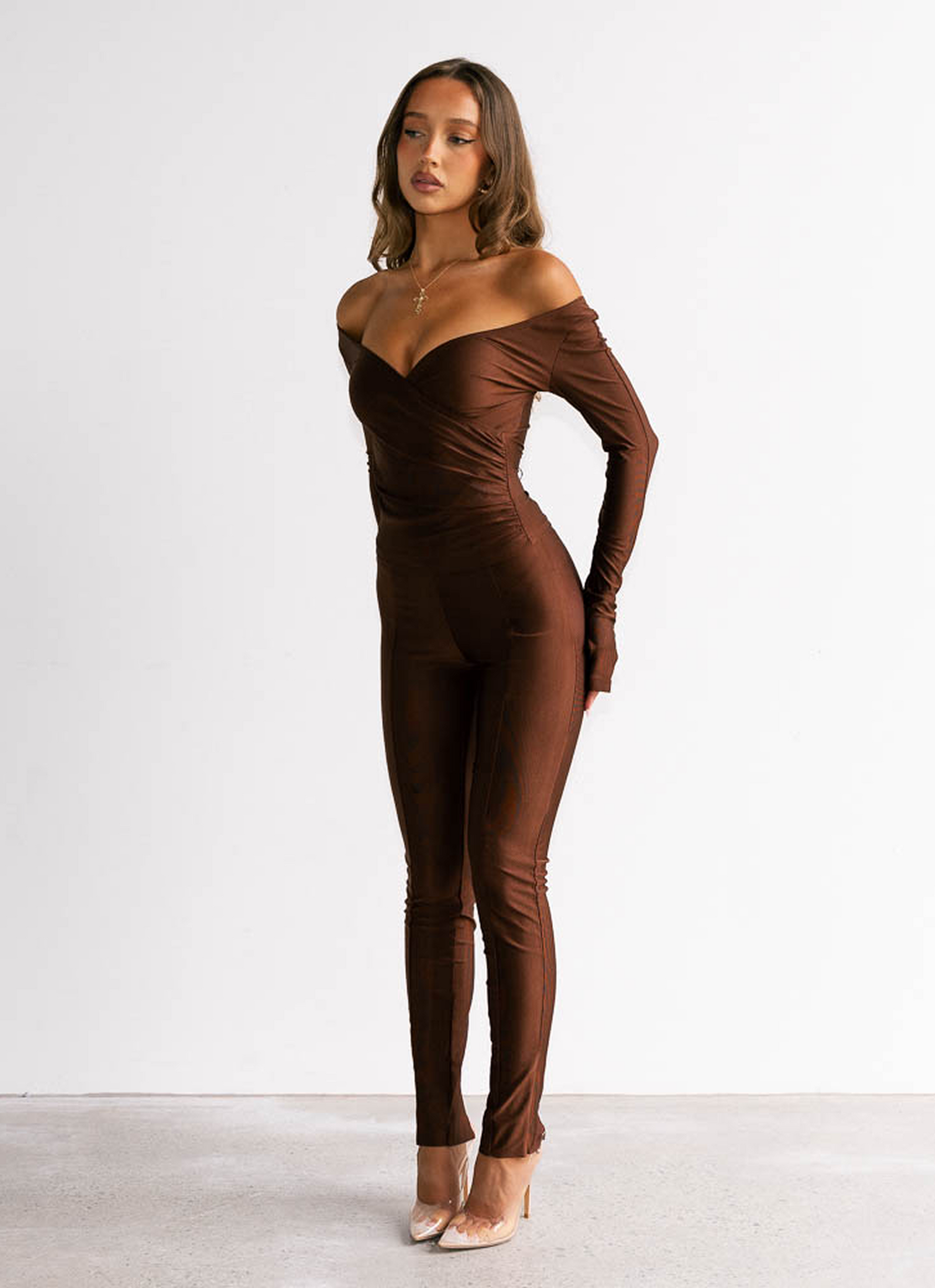 Woman wearing a brown off-shoulder jumpsuit on a white background