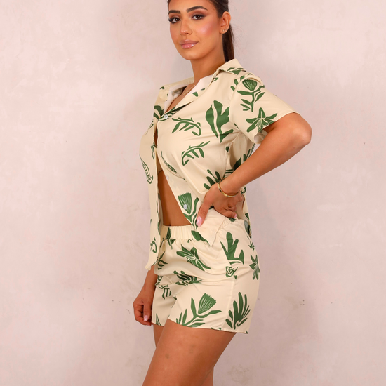 Woman wearing a tropical leaf print outfit on a plain background