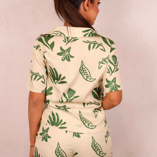 Person wearing a green and white leaf-patterned outfit against a plain background