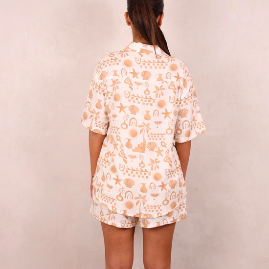 Person wearing a white outfit with peach floral pattern against a beige background