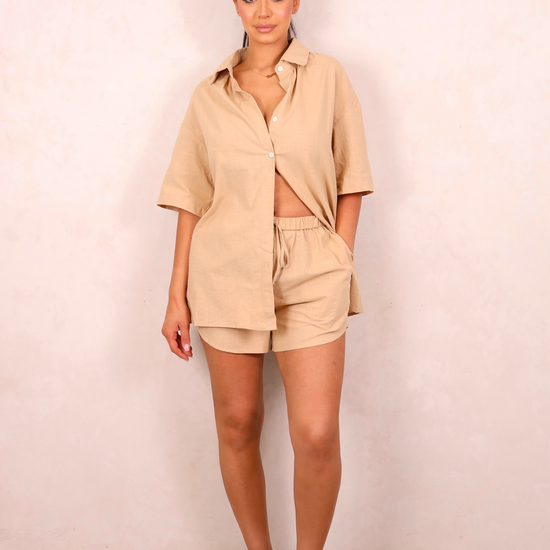 Woman wearing a beige outfit against a plain background