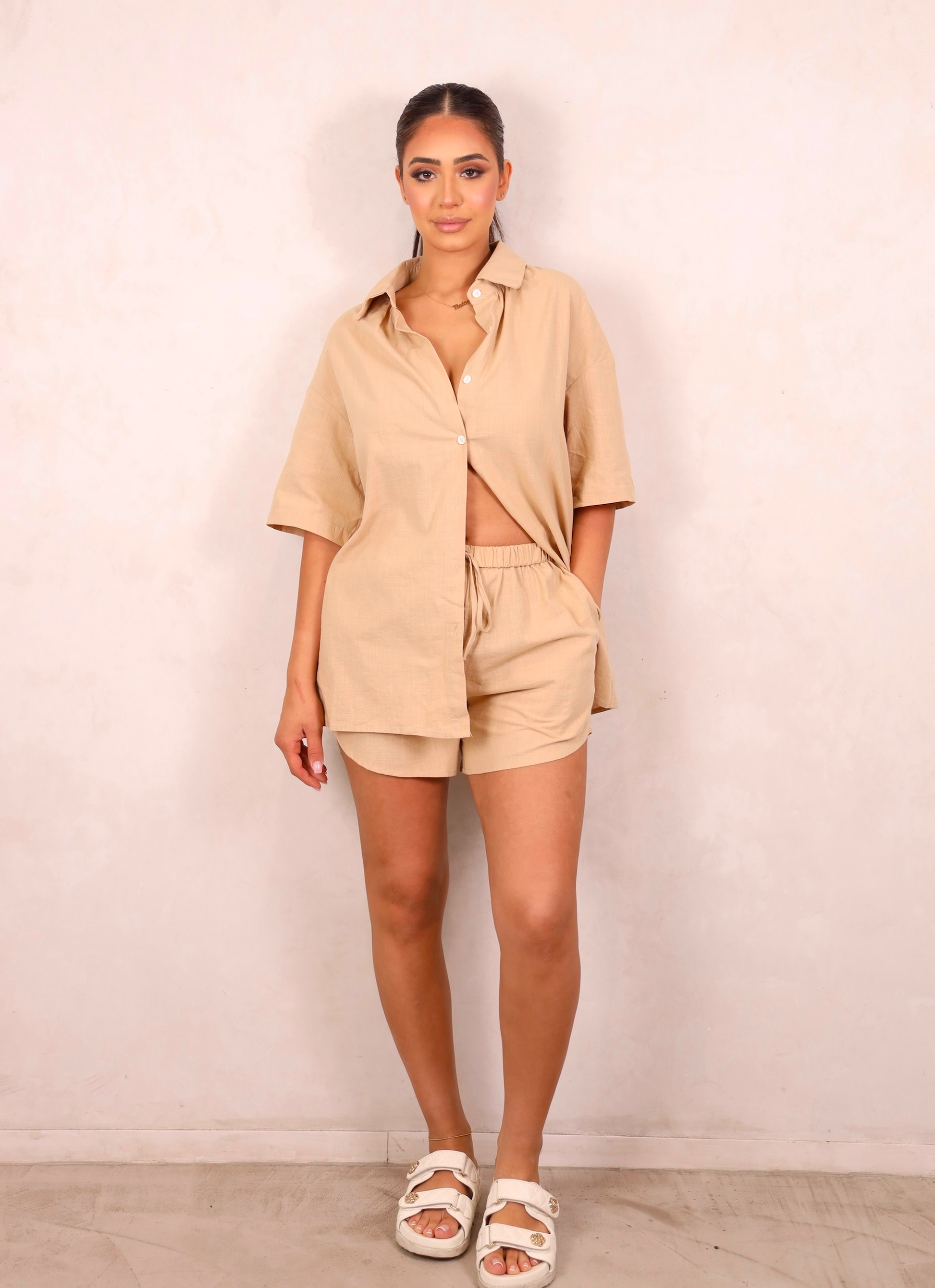 Woman wearing a beige outfit against a plain background