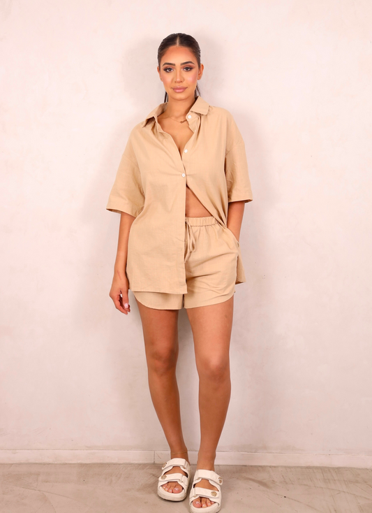 Woman wearing a beige outfit against a plain background