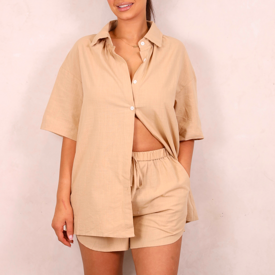 Woman wearing a beige shirt and shorts set against a plain background