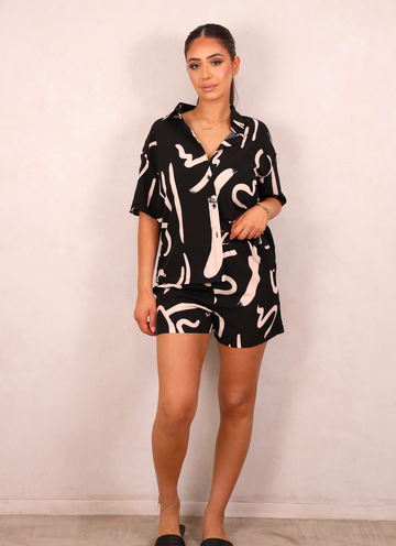 Woman wearing a black and white patterned outfit against a plain background