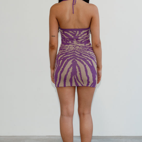 Woman wearing a purple and beige zebra print dress against a white background