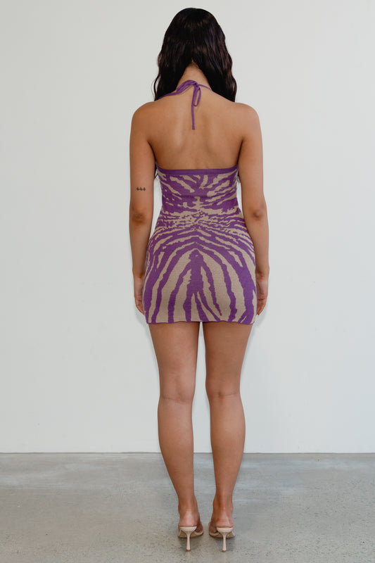 Woman wearing a purple and beige zebra print dress against a white background