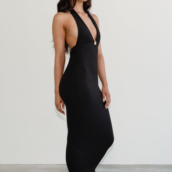 Woman wearing a black dress with a plunging neckline against a white background