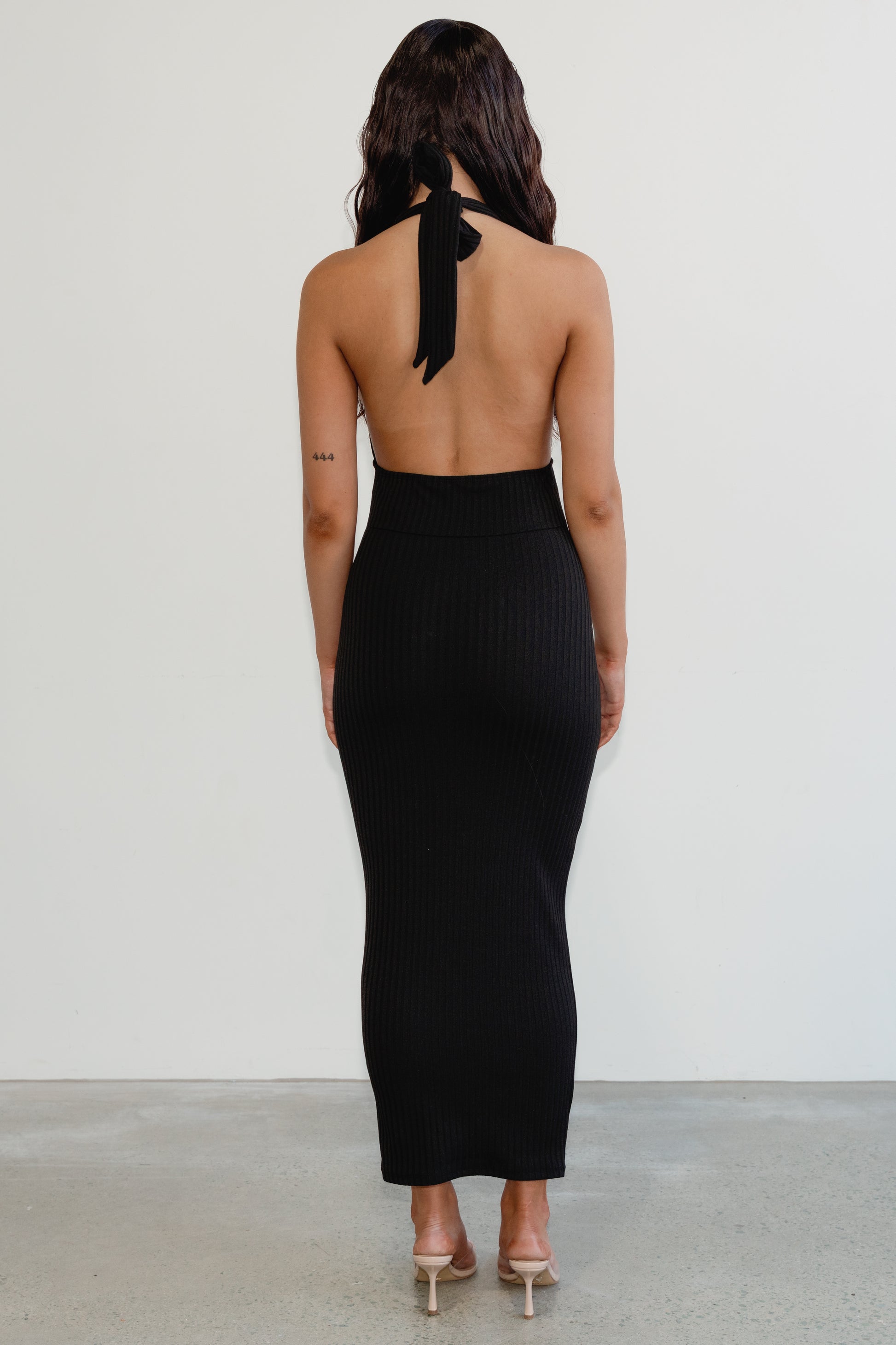 Woman wearing a black halter neck dress with a plain background