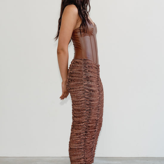 Woman wearing a brown textured dress against a white background