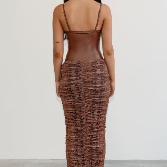 Woman wearing a brown textured dress with thin straps on a white background