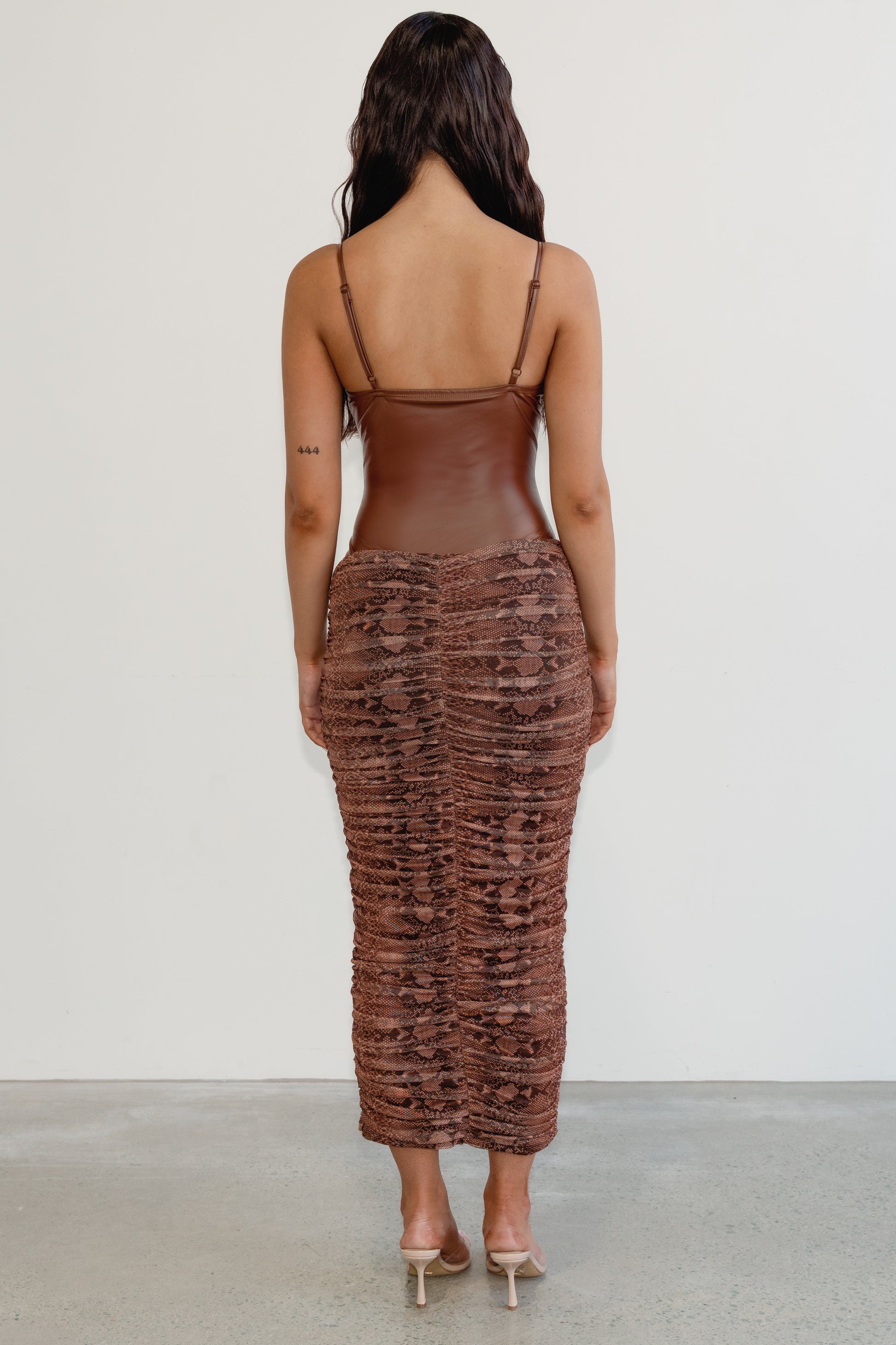 Woman wearing a brown textured dress with thin straps on a white background