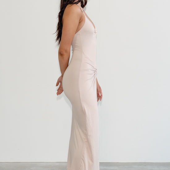 Woman wearing a light pink jumpsuit against a white background