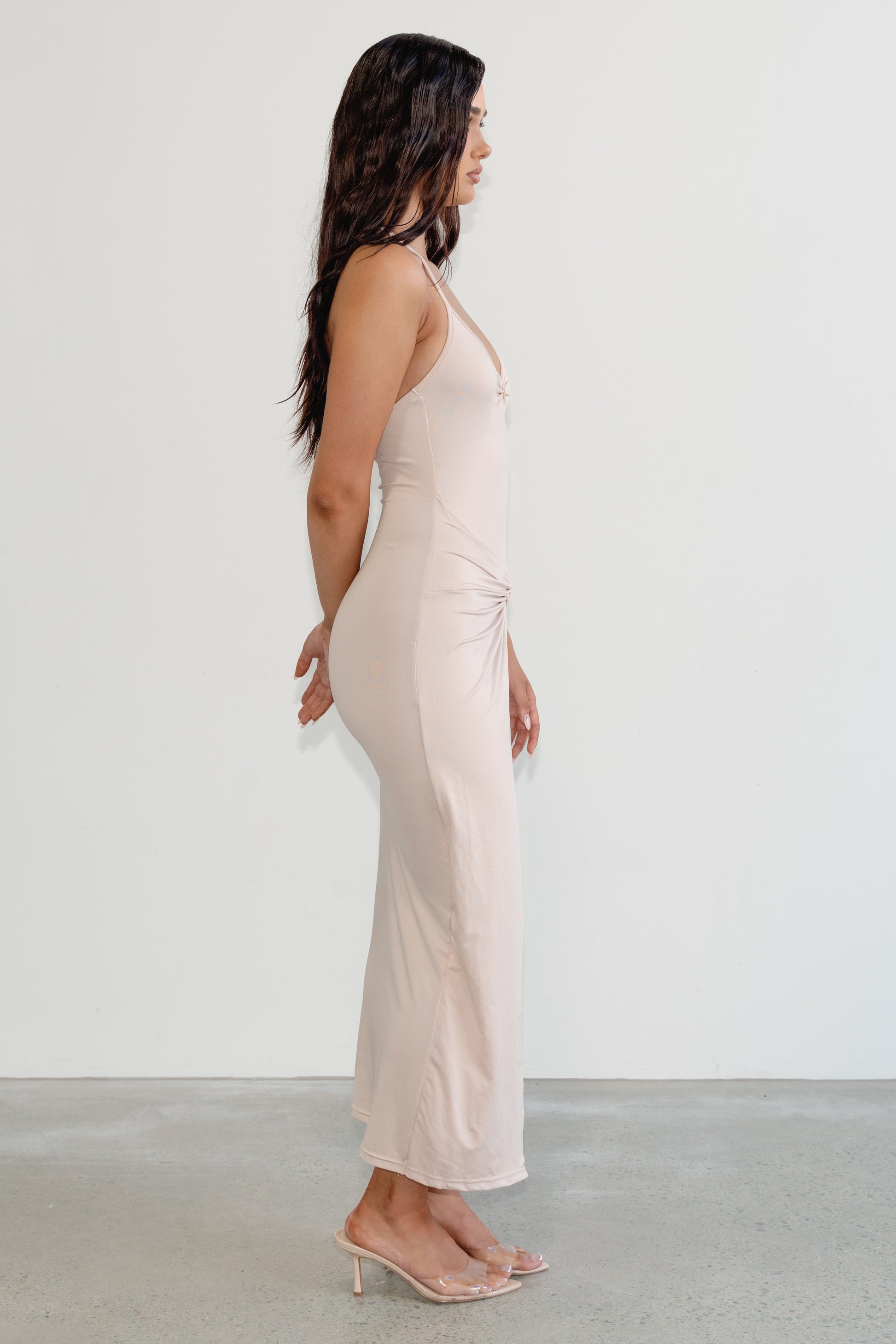 Woman wearing a light pink jumpsuit against a white background