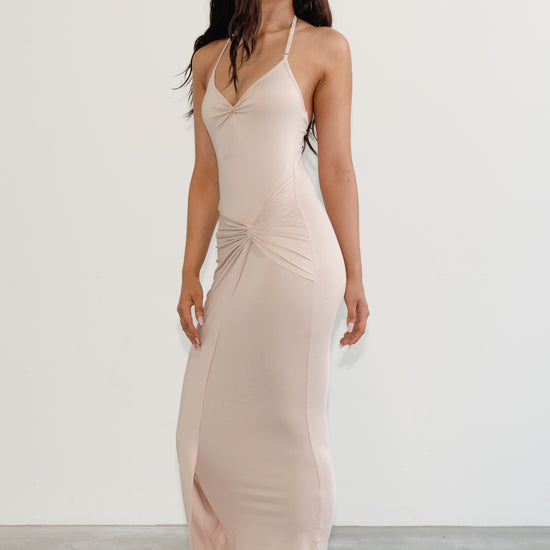 Woman wearing a beige halter neck dress against a white background