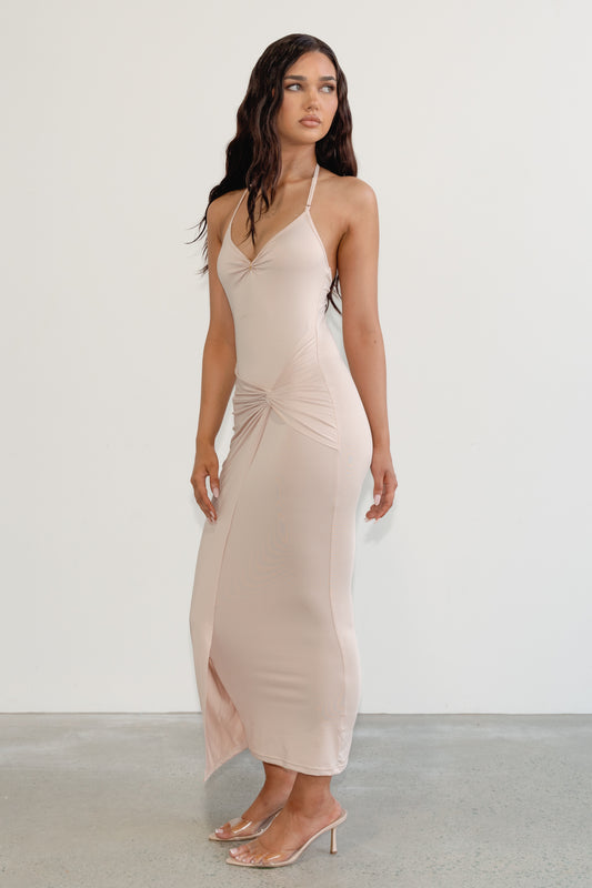 Woman wearing a beige halter neck dress against a white background