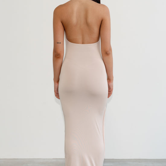 Woman wearing a beige strapless dress with a plain background