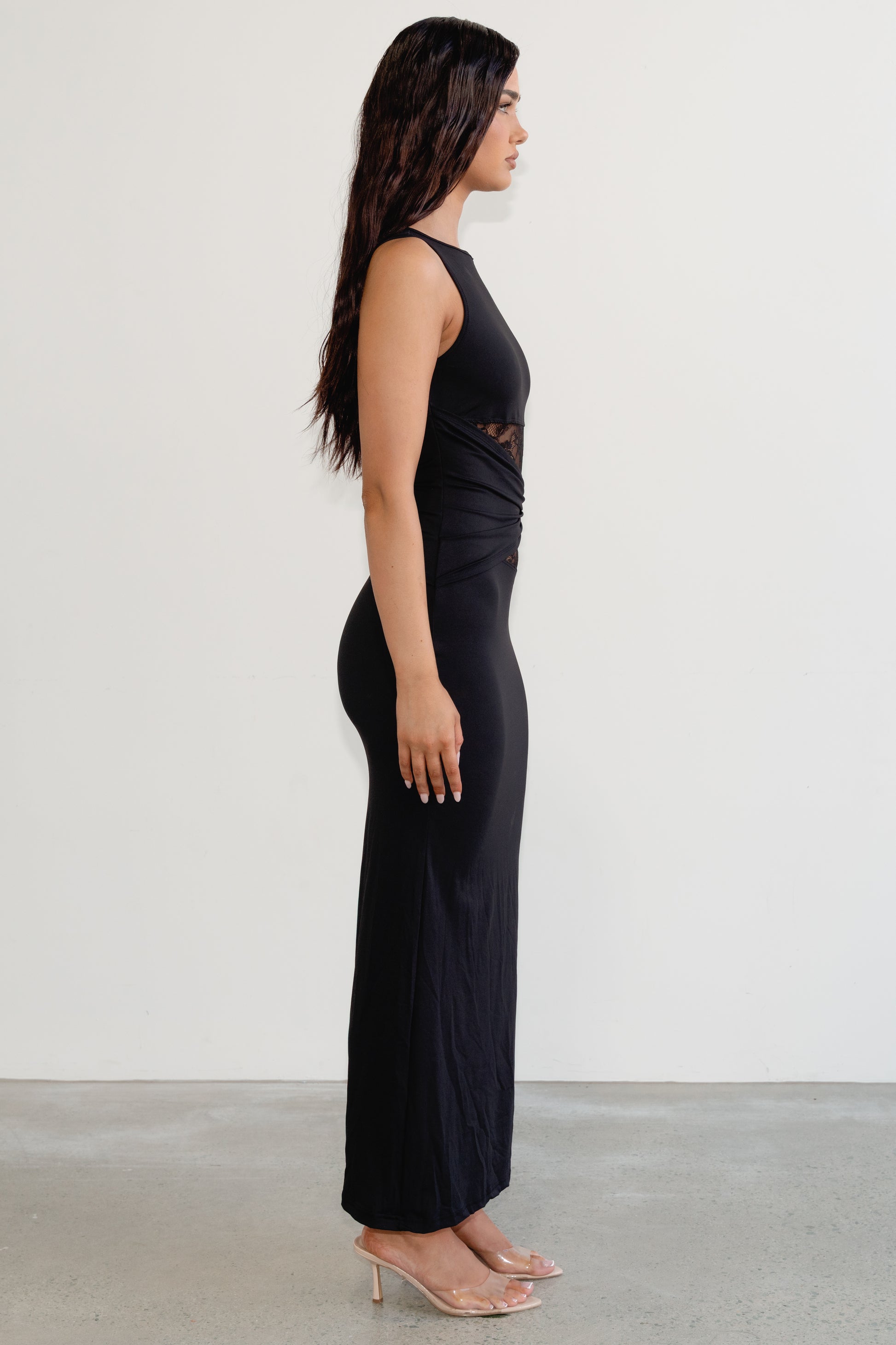 Woman wearing a black sleeveless top and high-waisted pants against a white background