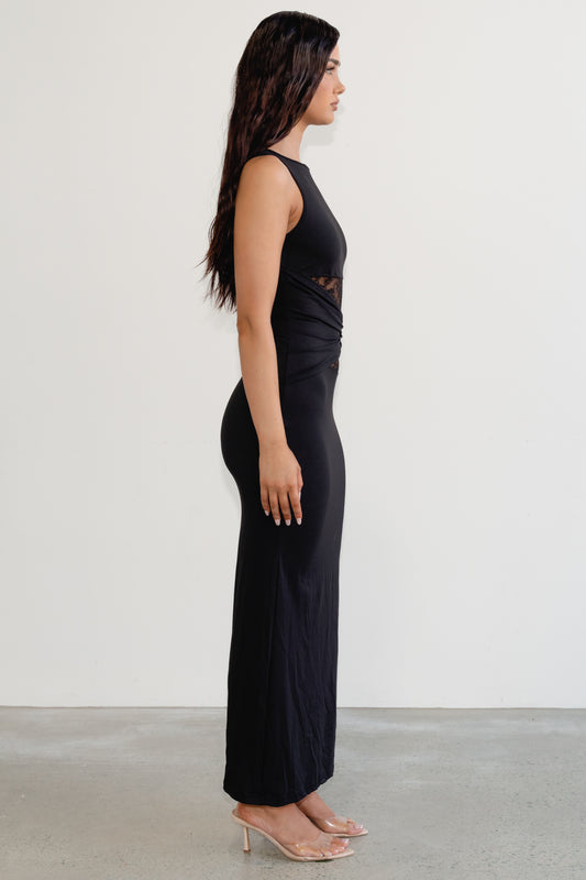 Woman wearing a black sleeveless top and high-waisted pants against a white background