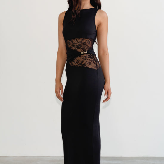 Woman wearing a black sleeveless dress with lace detailing on a white background