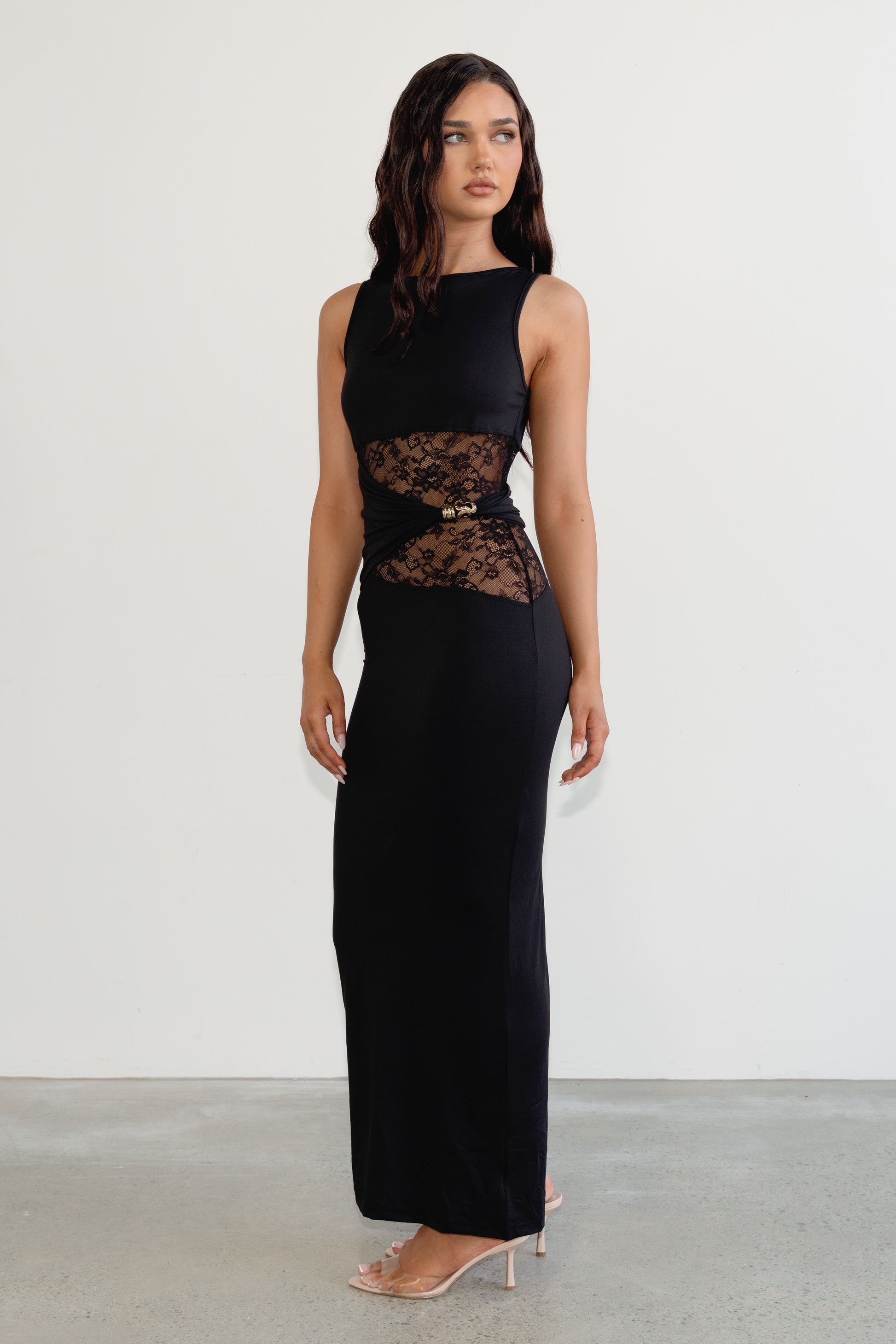 Woman wearing a black sleeveless dress with lace detailing on a white background