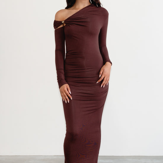 Woman wearing a burgundy off-shoulder dress against a white background