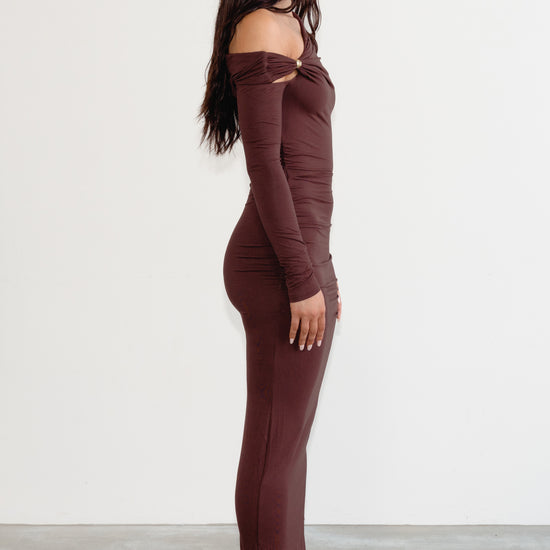 Woman wearing a brown off-shoulder jumpsuit on a white background