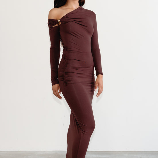 Woman wearing a brown off-shoulder dress against a white background