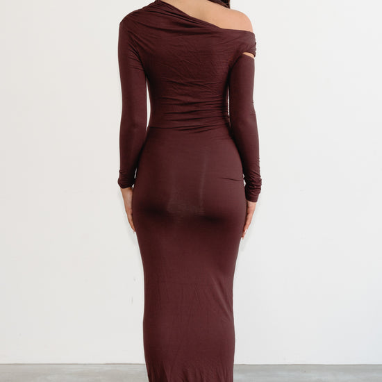 Woman wearing a burgundy one-shoulder dress against a white background