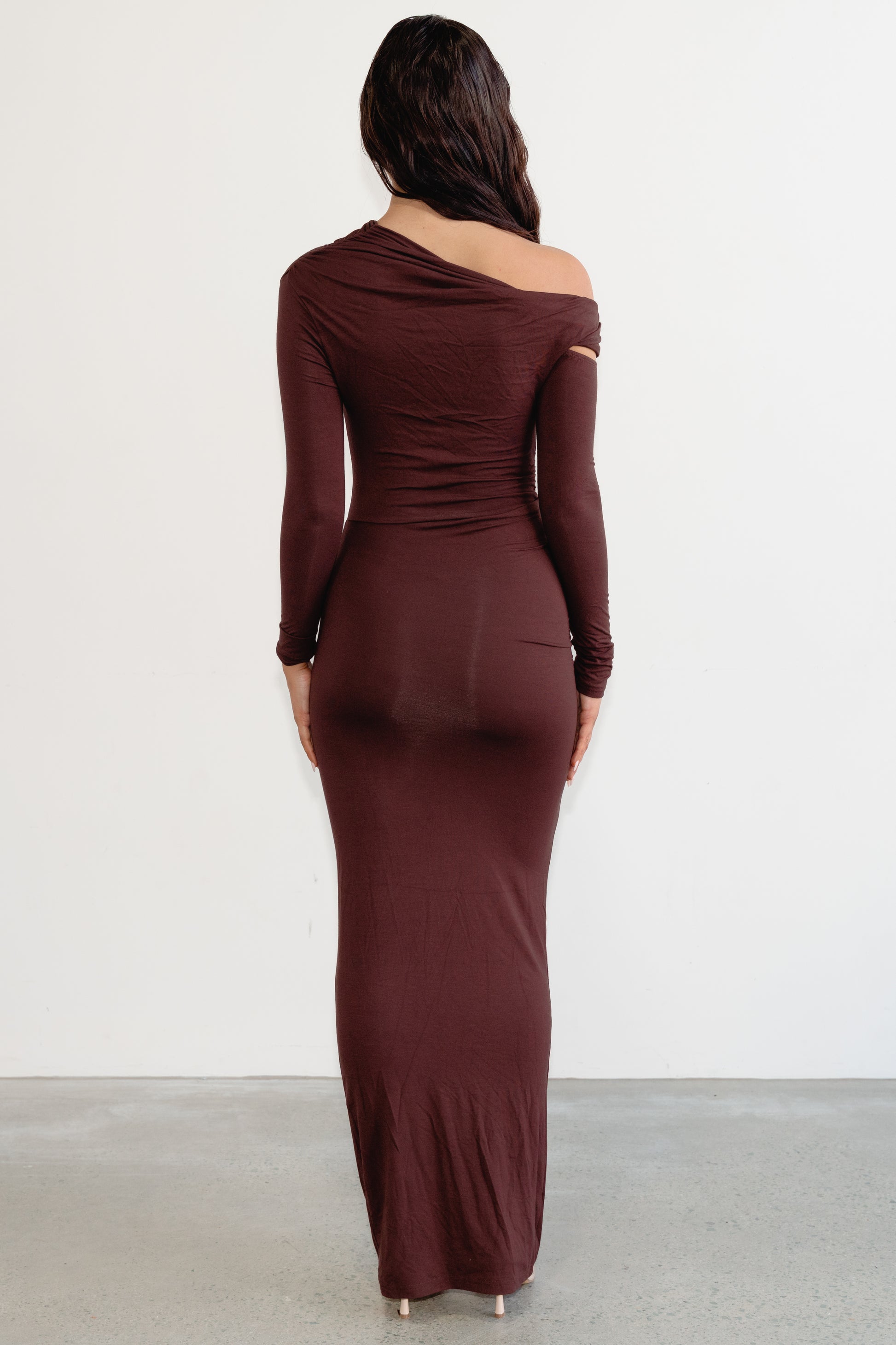 Woman wearing a burgundy one-shoulder dress against a white background