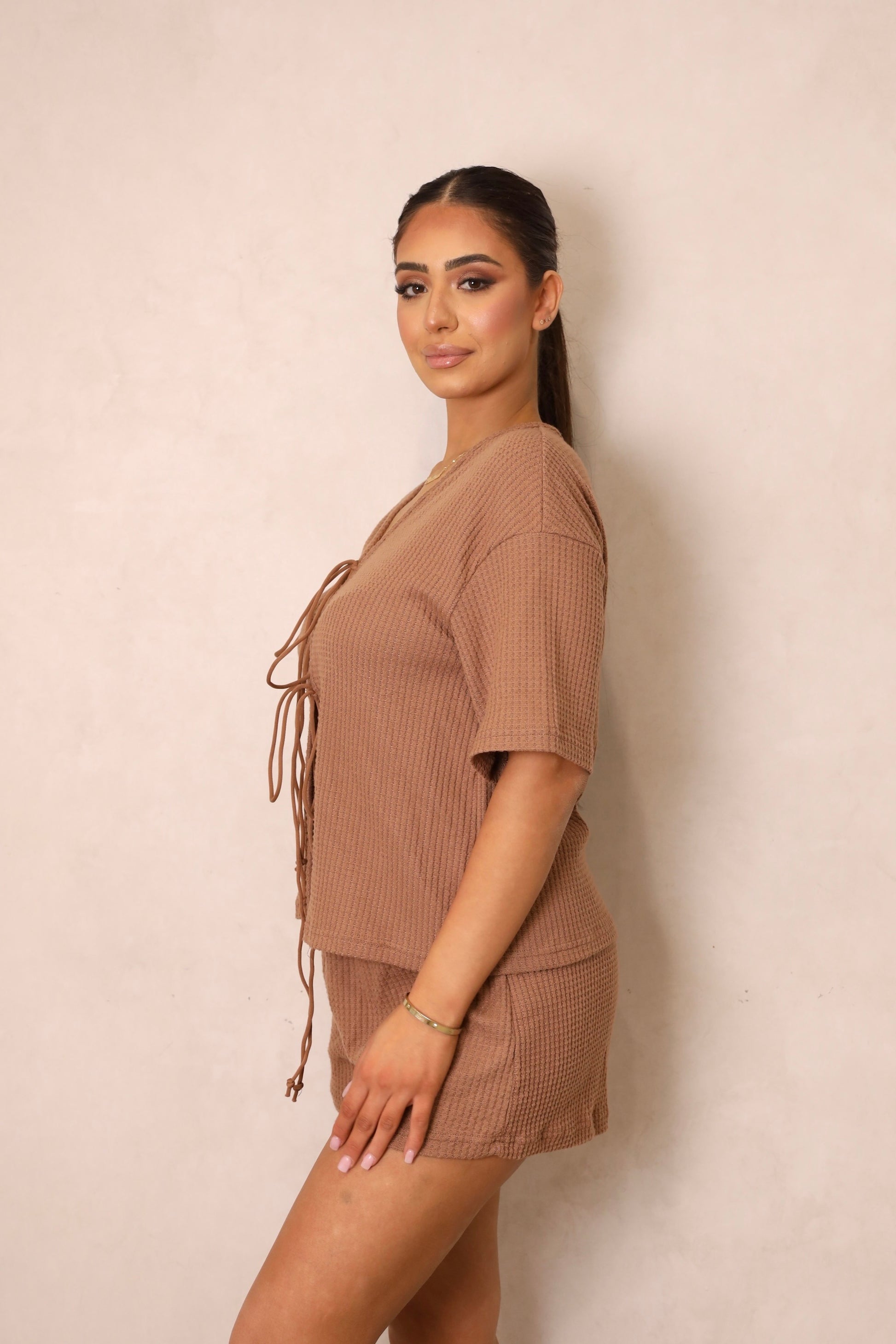 A woman wearing a brown tie-front crop top and matching shorts with a drawstring waist.