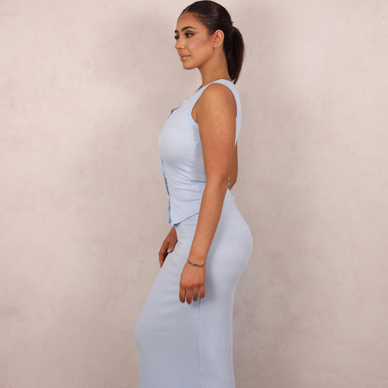 A model wearing a baby blue ribbed knit two-piece set with a button-up tank and matching maxi skirt.