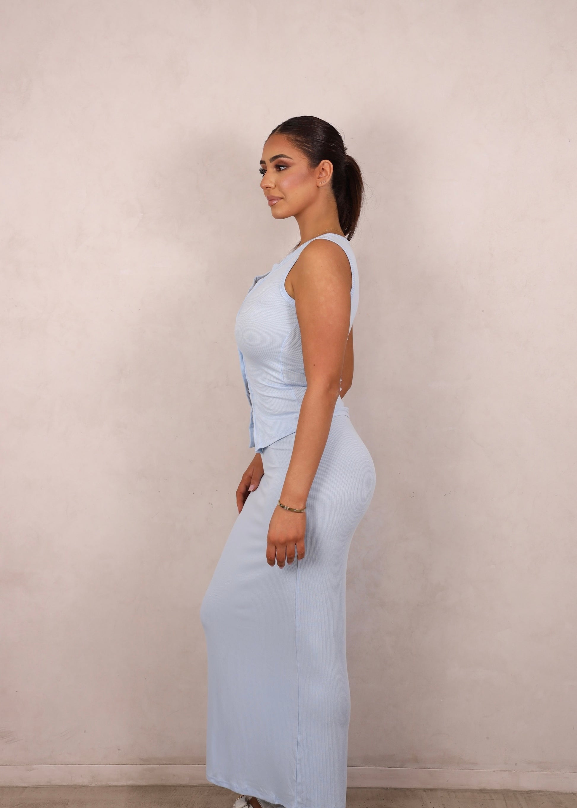 A model wearing a baby blue ribbed knit two-piece set with a button-up tank and matching maxi skirt.