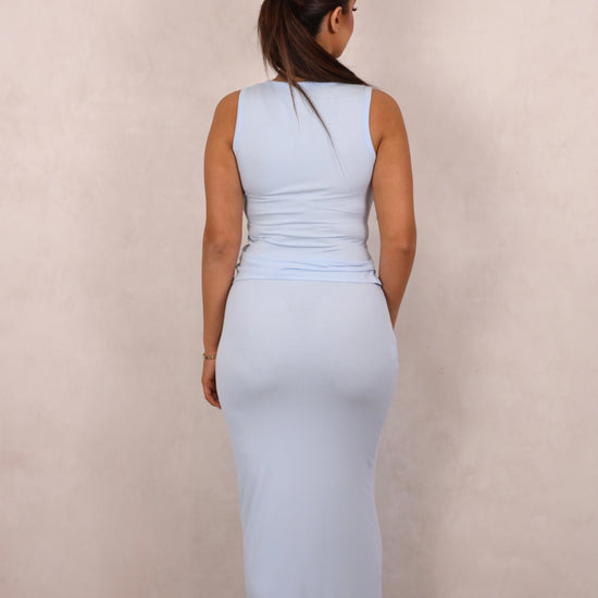 A model wearing a baby blue ribbed knit two-piece set with a button-up tank and matching maxi skirt.