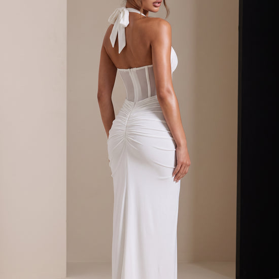 Amaya Sheer Corset Halter Maxi Dress in white, back view showing the halter bow, sheer corset panels and ruched dress.